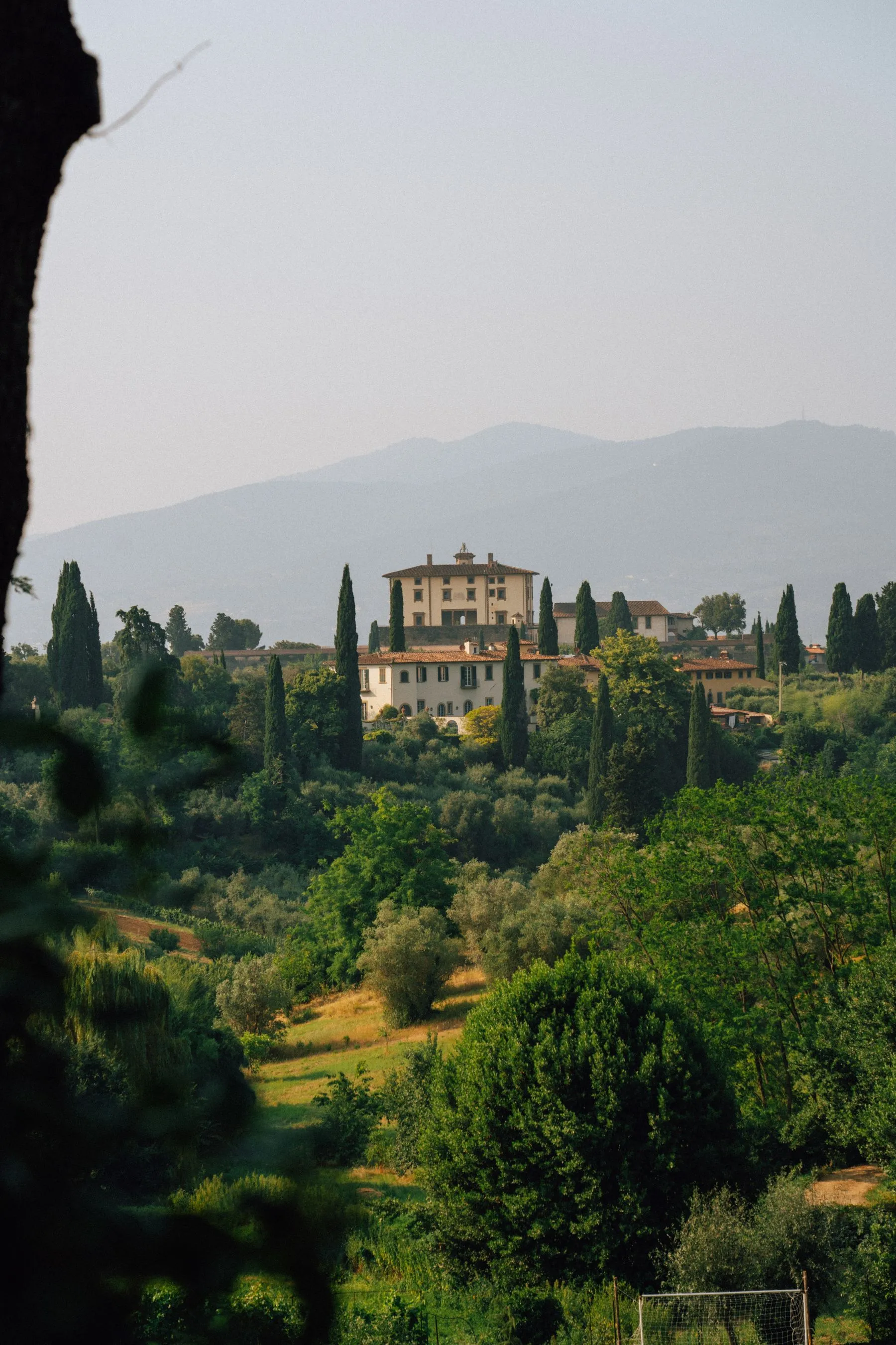 A warm stone villa overlooking the green Tuscan hills and cypress trees.